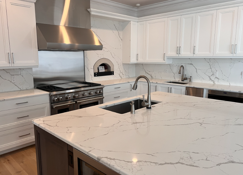 A kitchen with white cabinets , granite counter tops , stainless steel appliances and a large island.