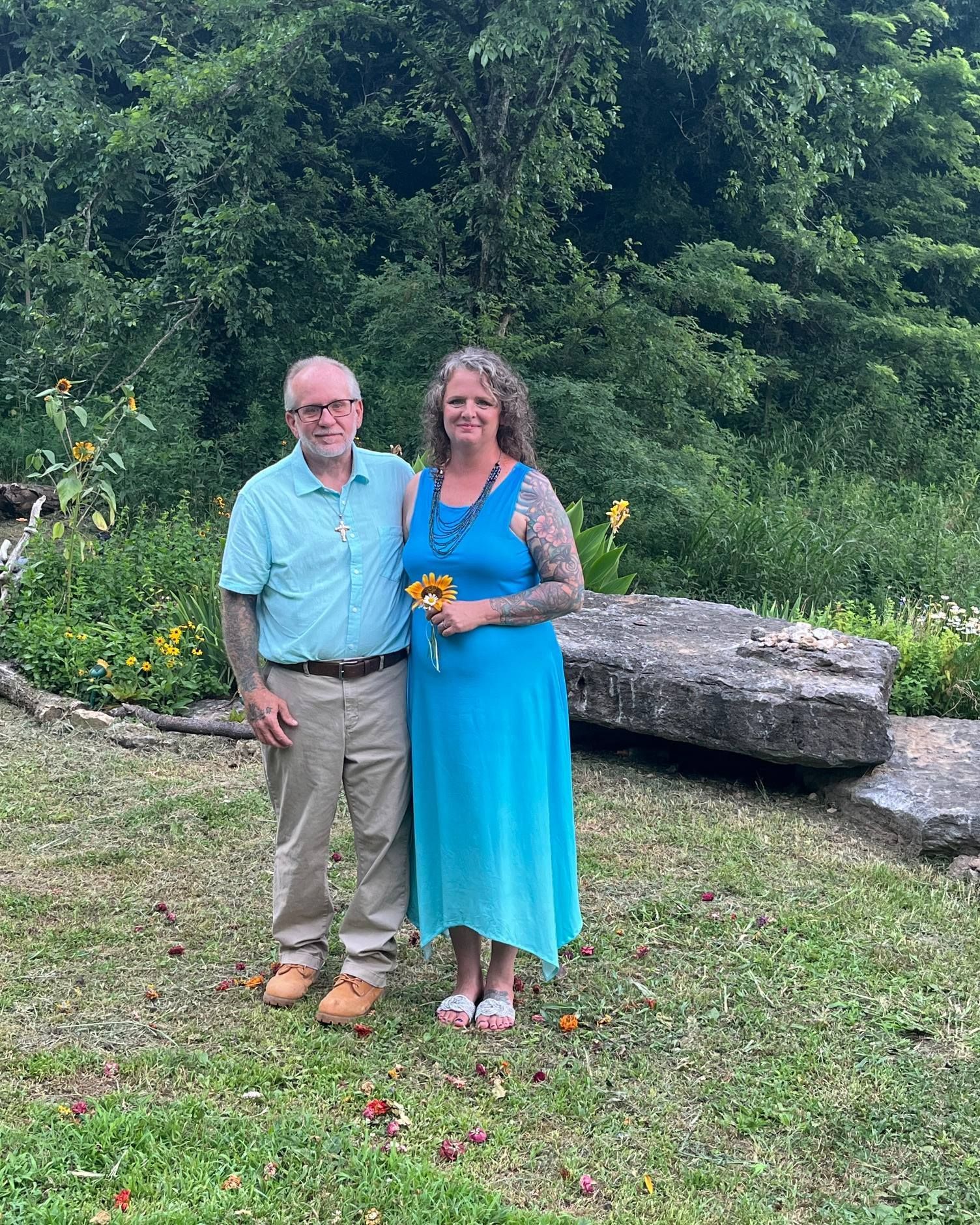 A man and a woman are standing next to each other in a grassy field.