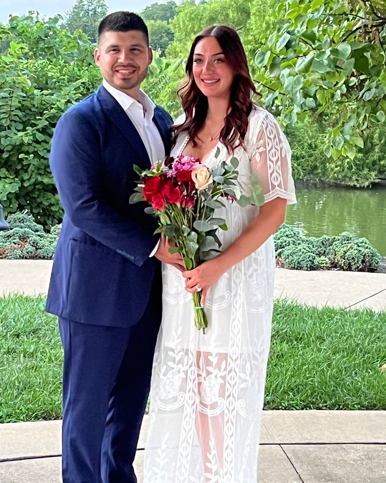 A man in a suit and a woman in a white dress are posing for a picture.