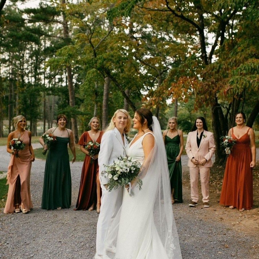 A bride and groom are posing for a picture with their bridesmaids.