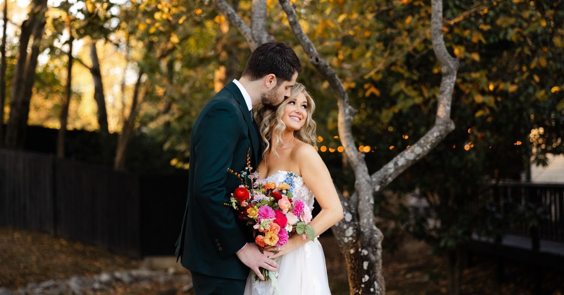 A bride and groom are posing for a picture in front of a tree.