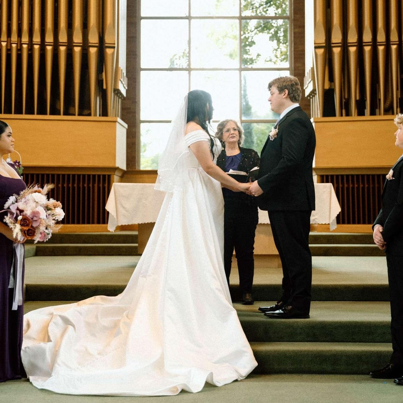 A bride and groom hold hands during their wedding ceremony.