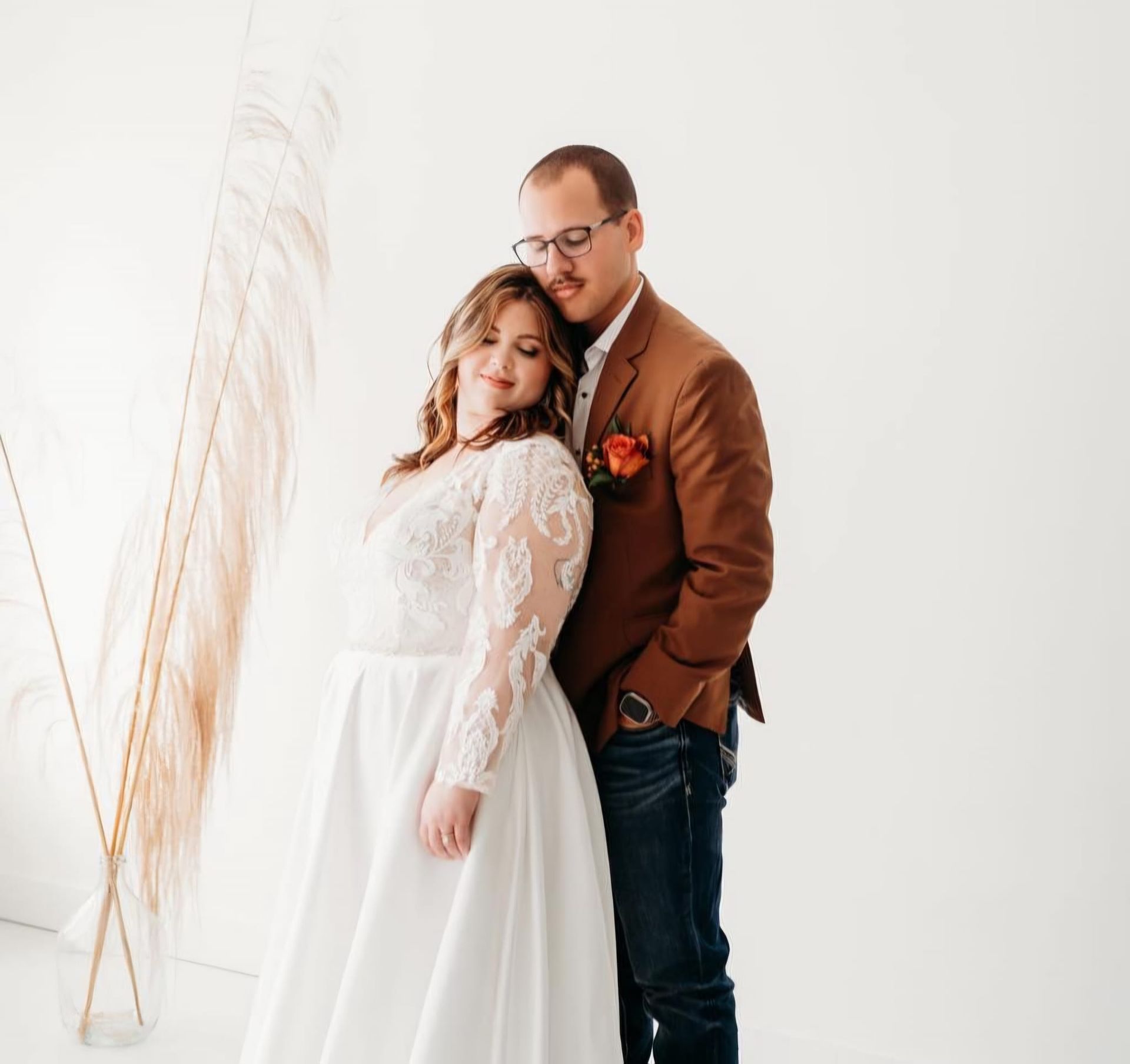A bride and groom are posing for a picture in front of a white wall.