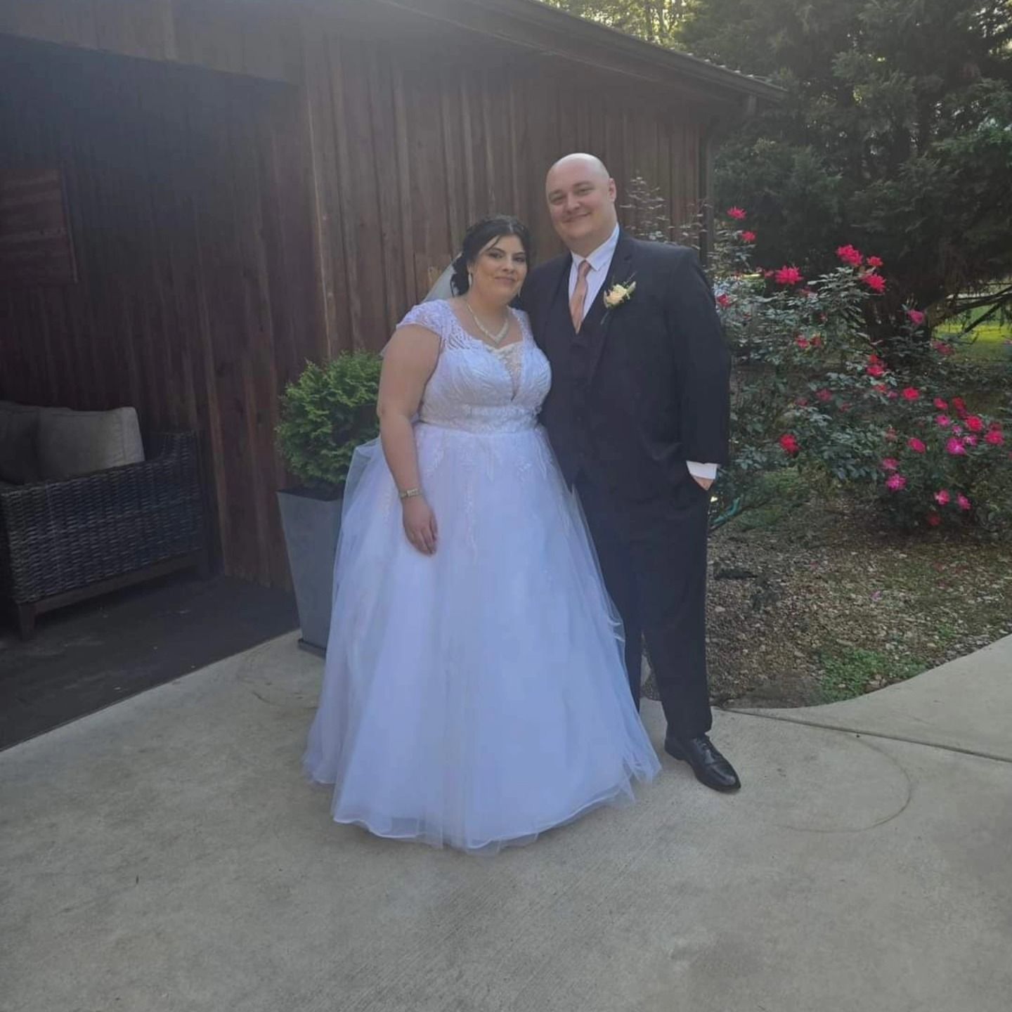 A bride and groom are posing for a picture in front of a wooden building.