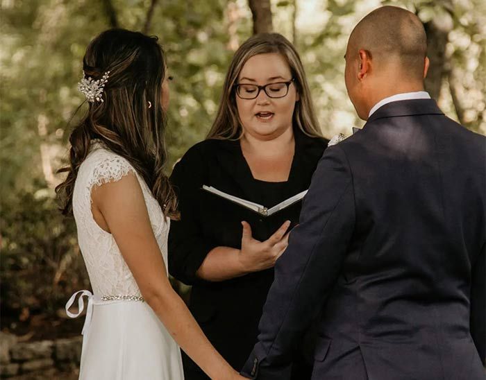 A bride and groom are holding hands during a wedding ceremony.