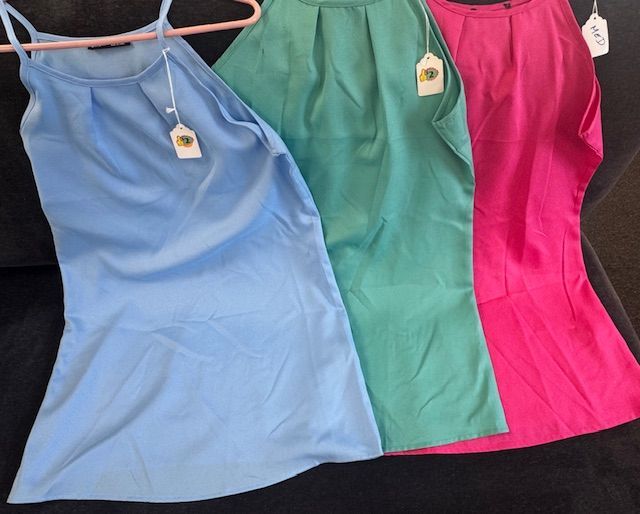 Three different colored dresses are sitting on a couch