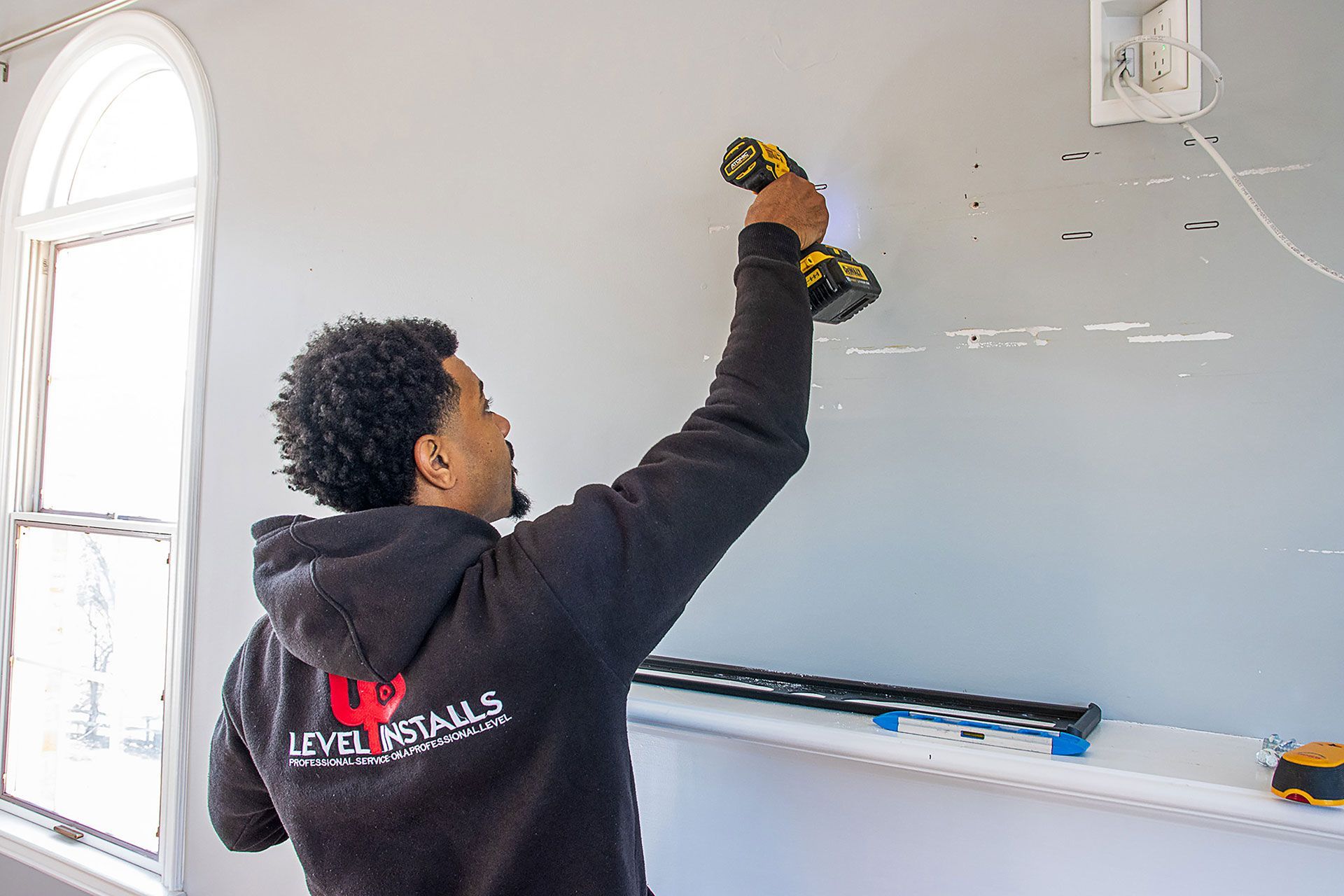 man drilling the wall for the TV