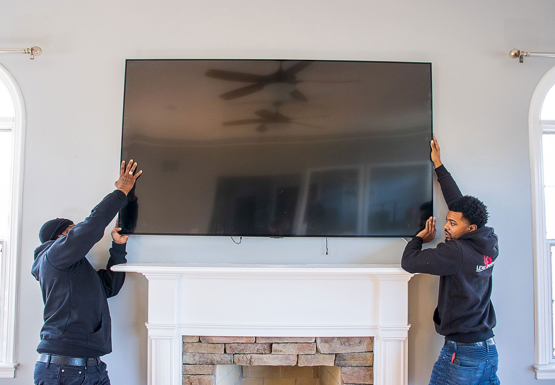 two men mounting the TV on the wall