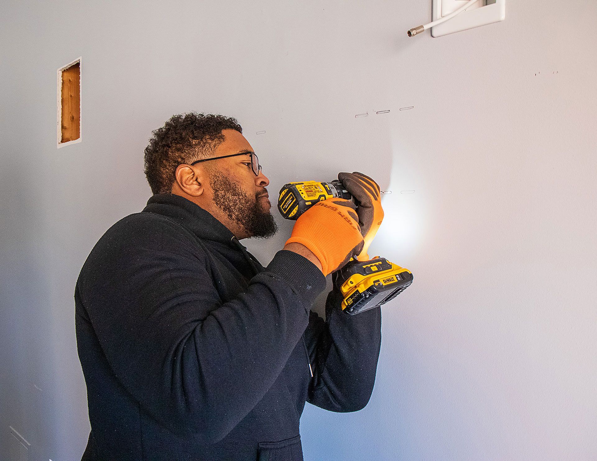 man drilling a hole on the wall