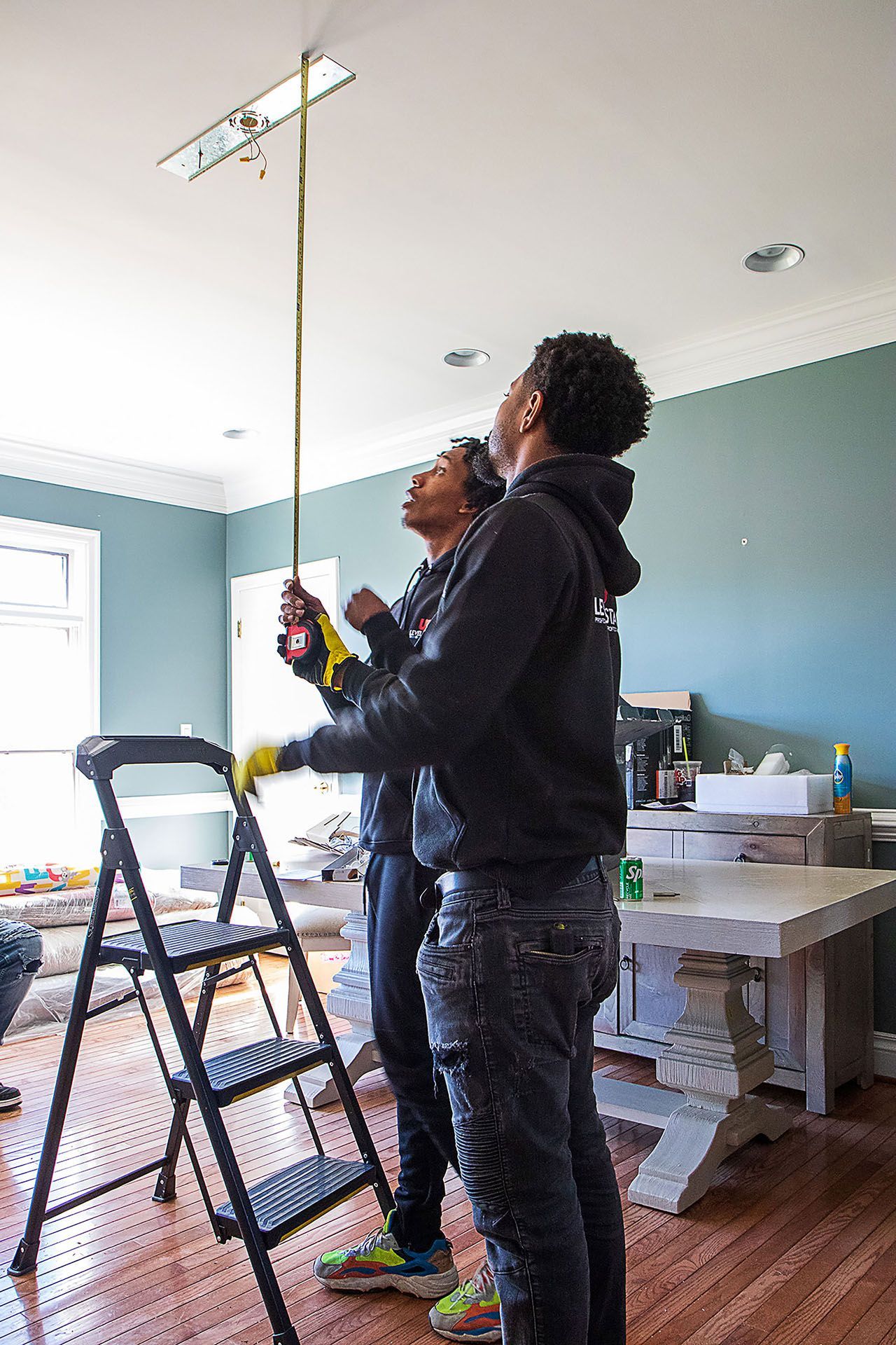 two men measuring the height of the hanging lights