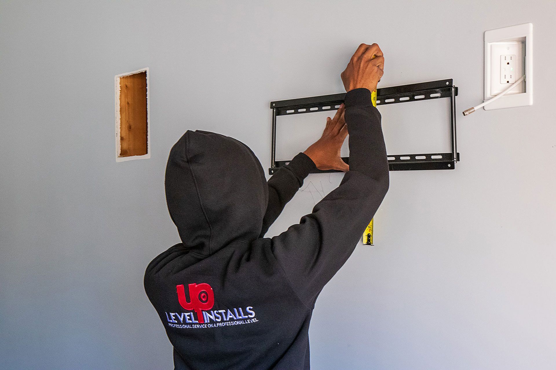 man measuring the TV bracket