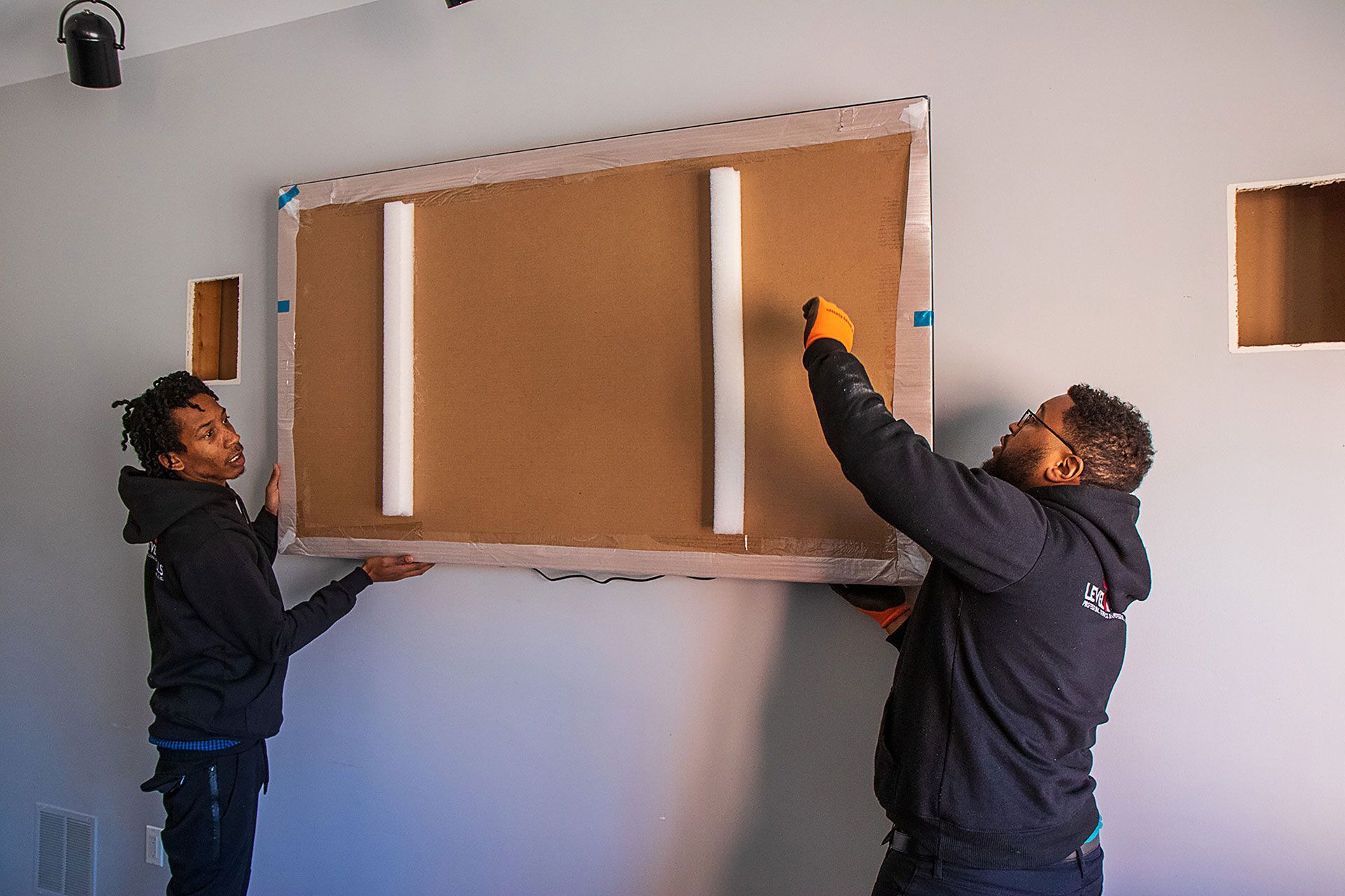 men carrying the wood that will hold the TV