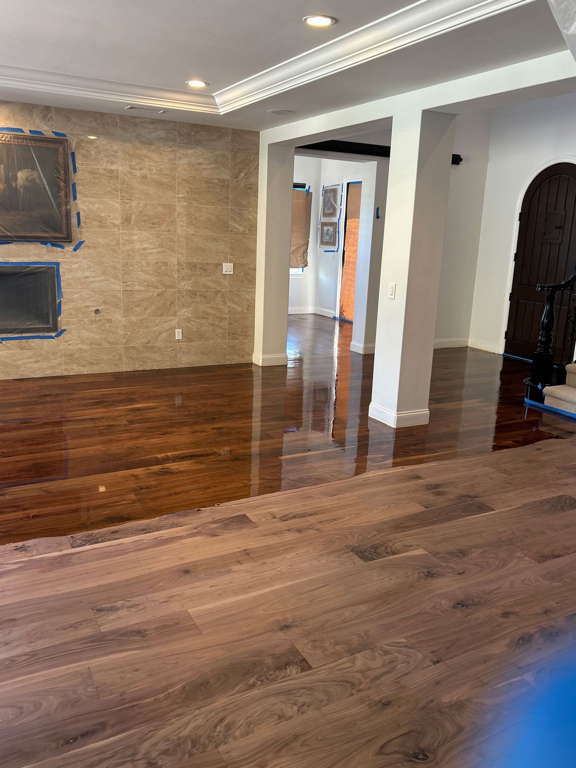 Empty living room with dark wood floors, textured wall, recessed lights, and an open doorway.
