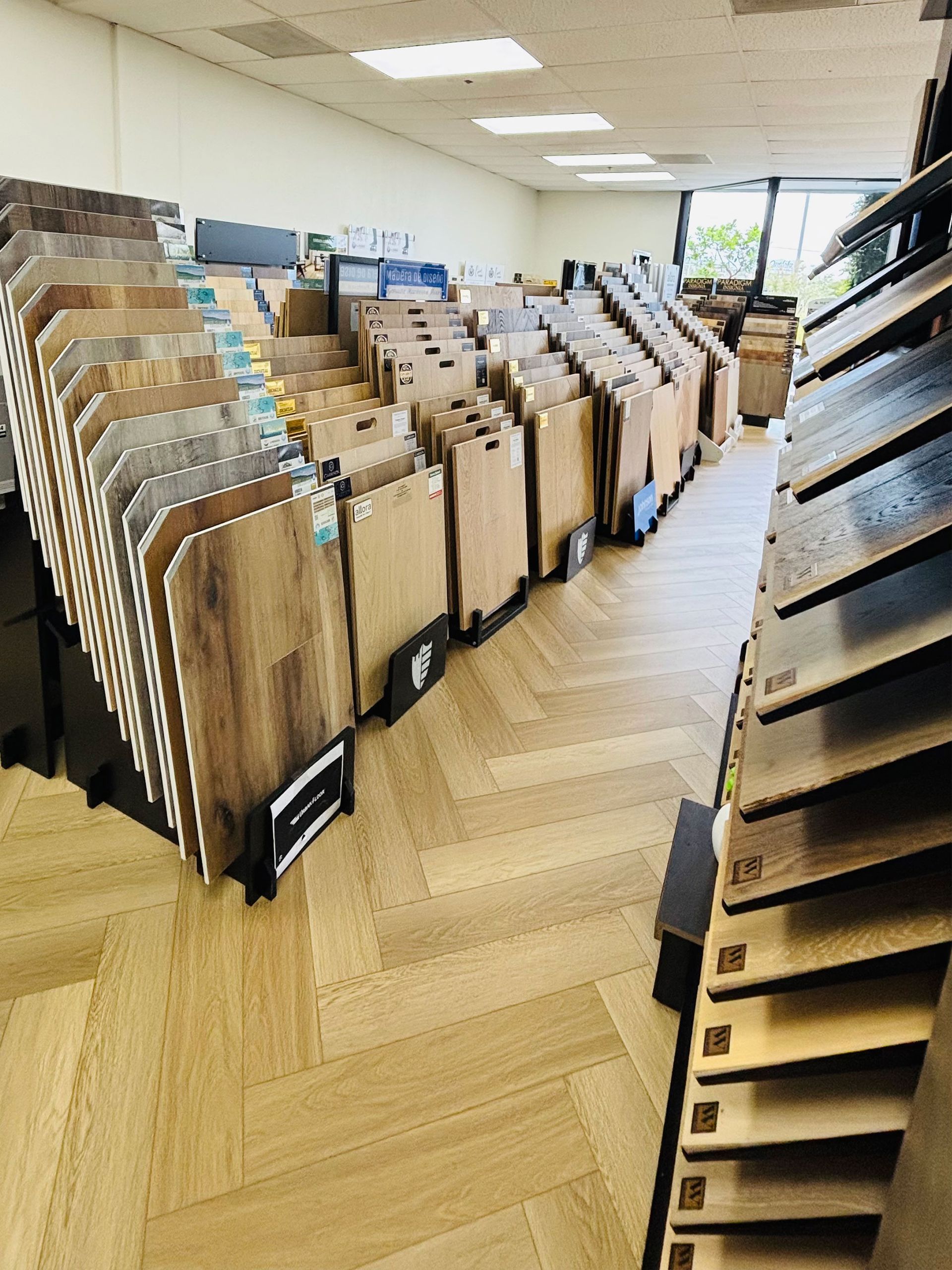Rows of wooden flooring samples displayed in a showroom with bright overhead lighting.