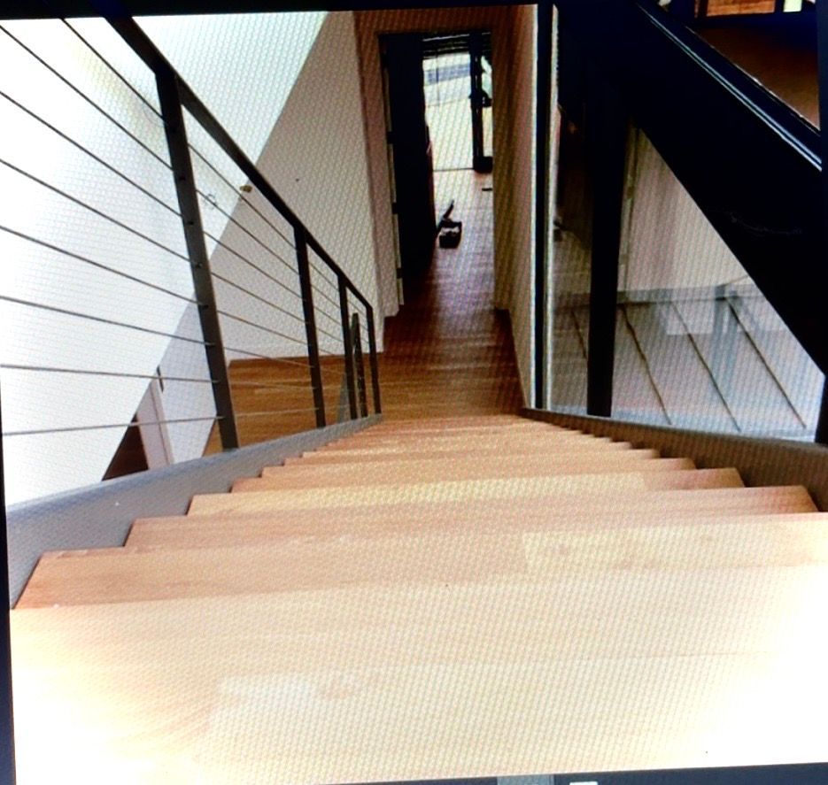View down a wooden staircase with black railings in a modern interior hallway