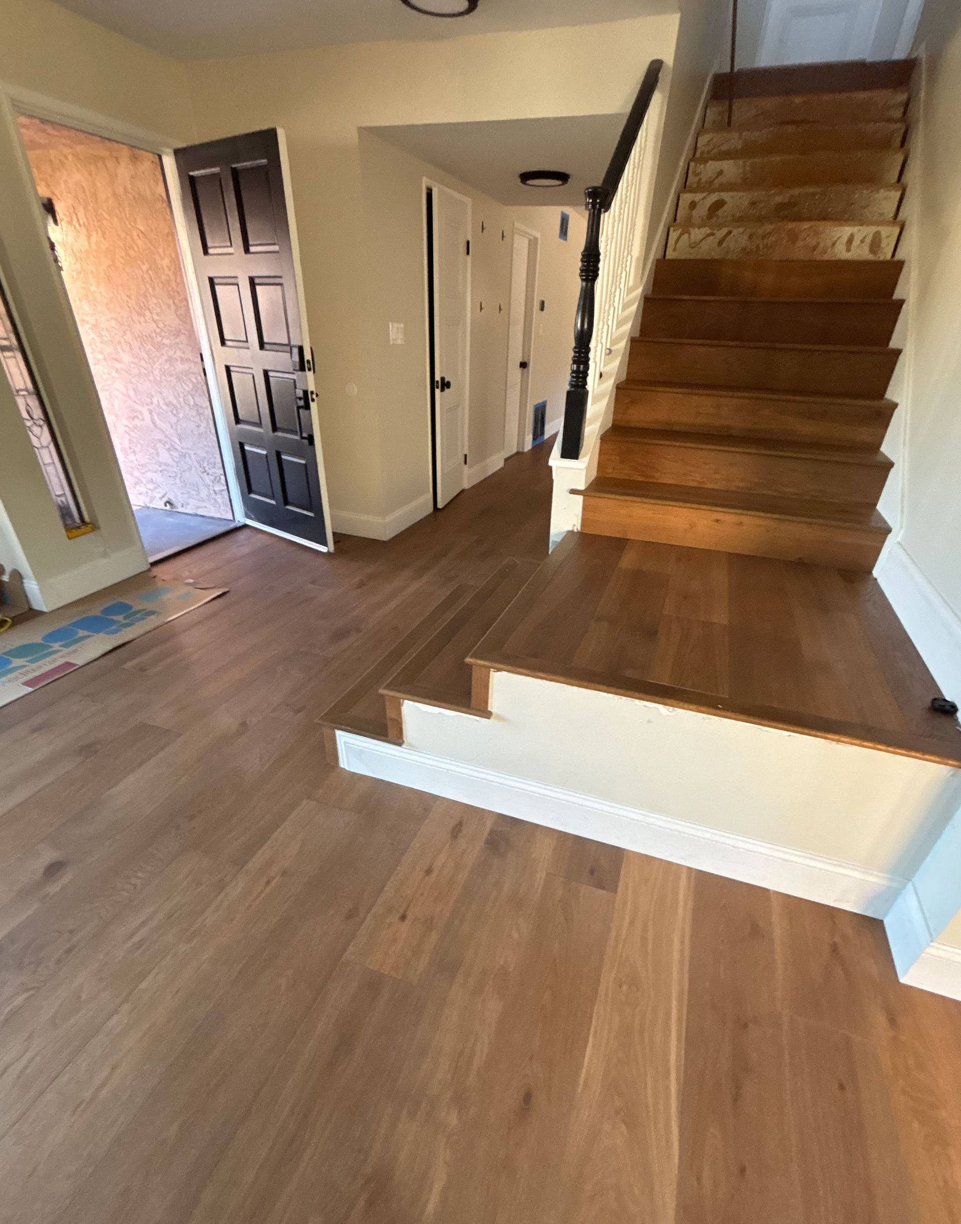 Interior foyer with wood floors, staircase, and a small step down to the entryway.