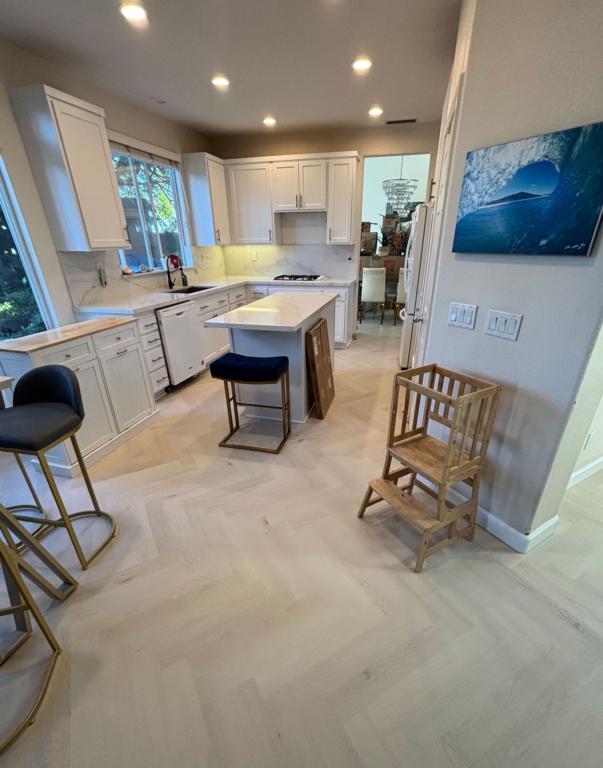 Bright modern kitchen with white cabinets, island seating, and blue wall art