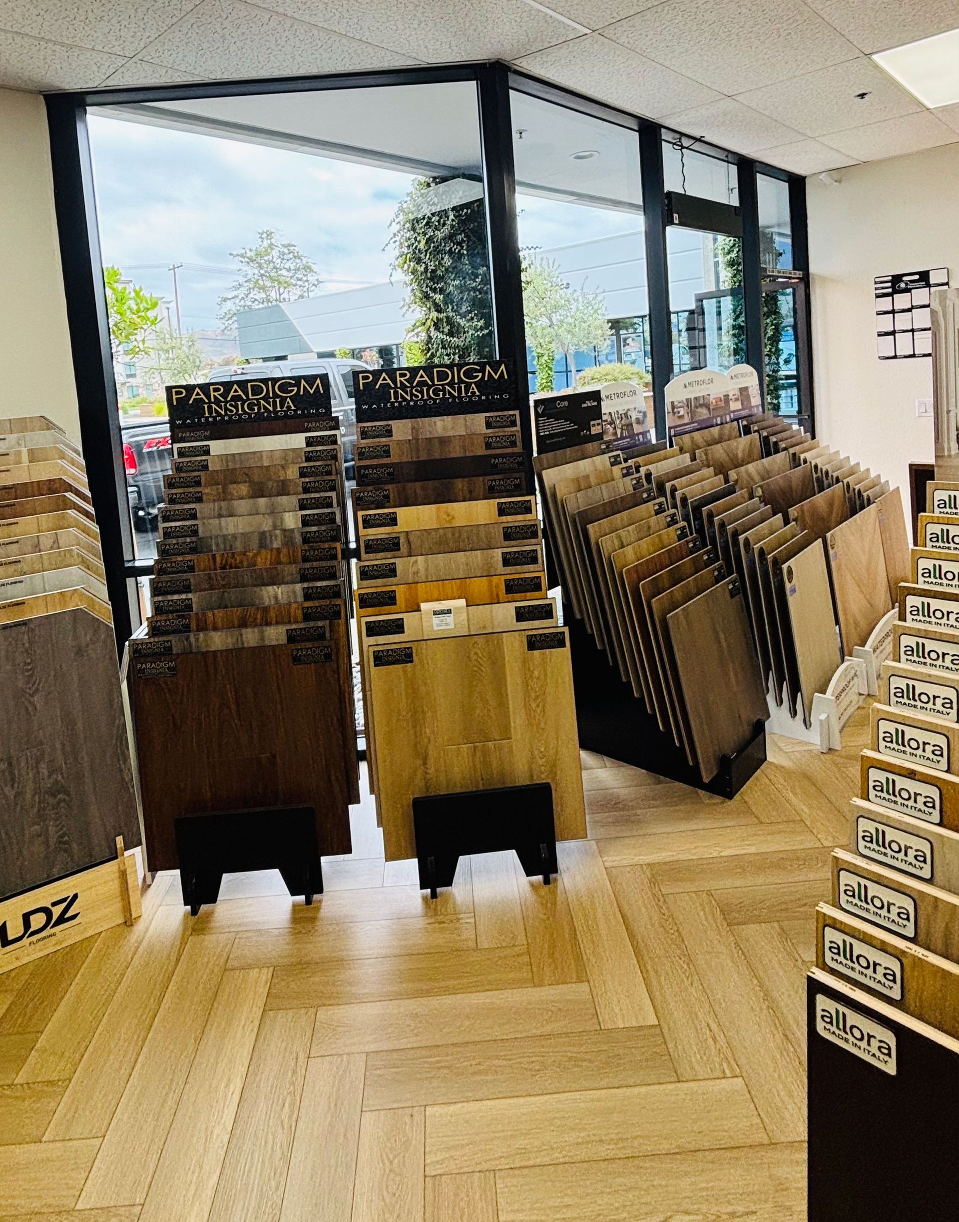 Bright bookstore with rows of angled book displays and a wood floor near large front windows