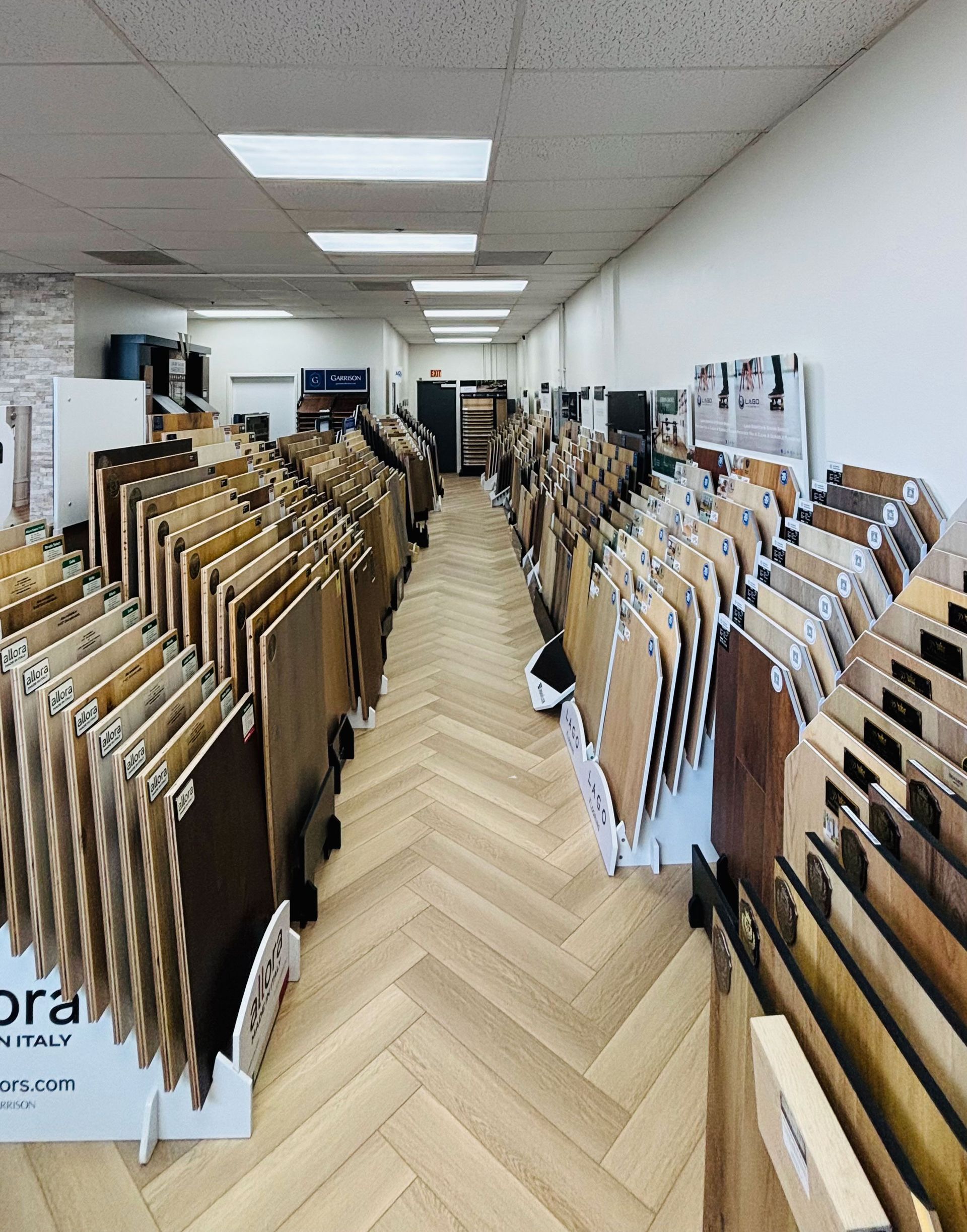 A showroom aisle lined with rows of large hanging wood floor samples.