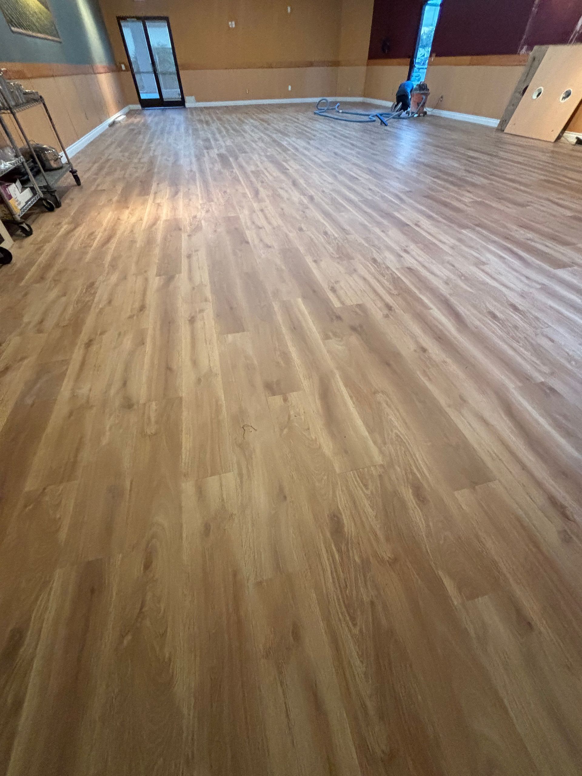 Empty indoor room with wood-look flooring and a blue padded column near the back wall