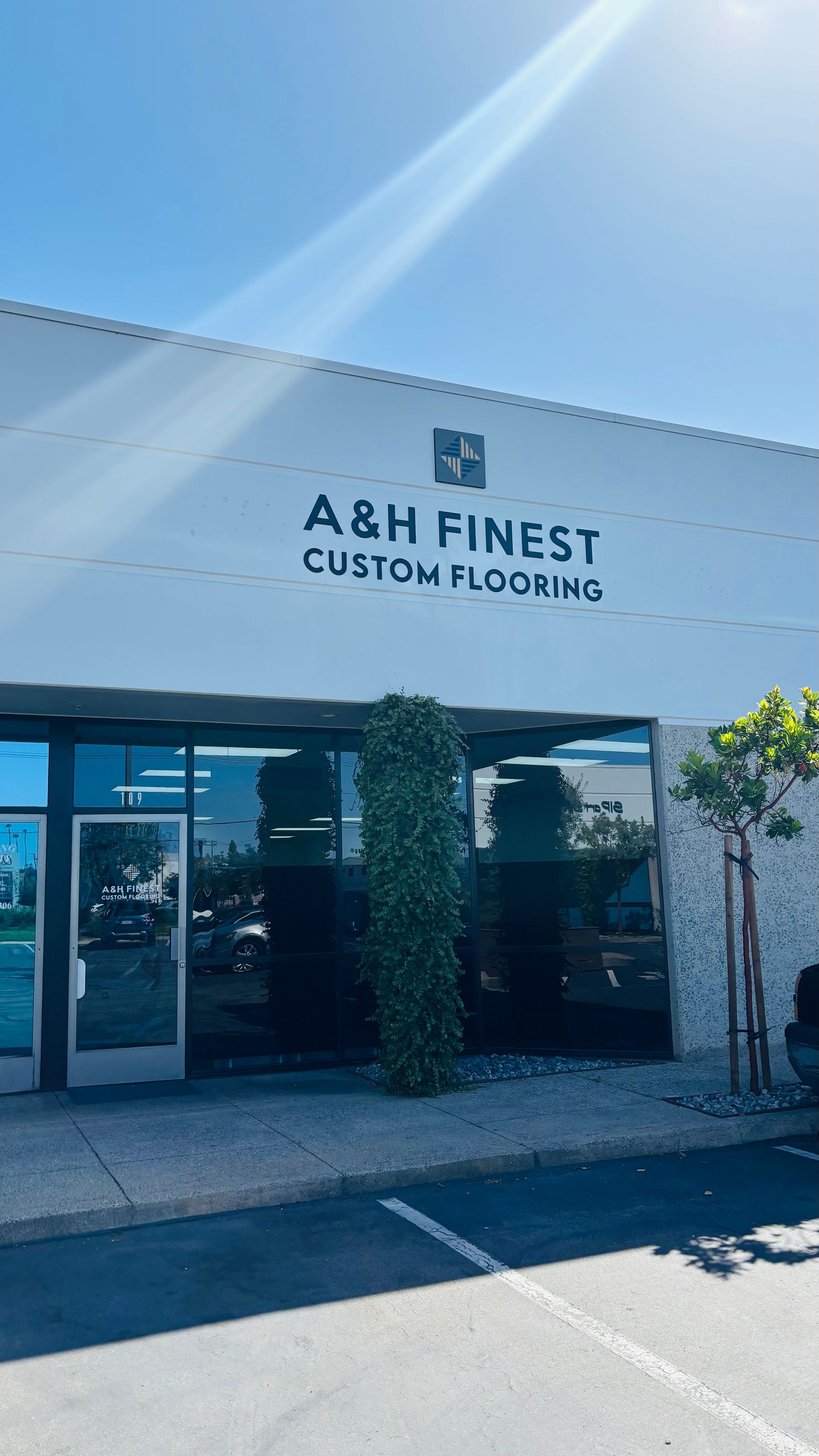 Storefront for A&H Finest Custom Flooring with white facade and glass entrance under a blue sky