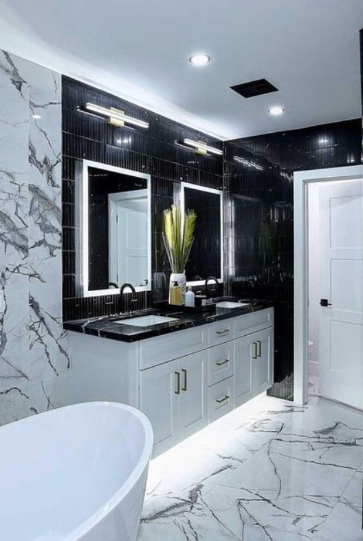 Modern bathroom with white and black marble, double vanity with black countertops, and a freestanding tub.