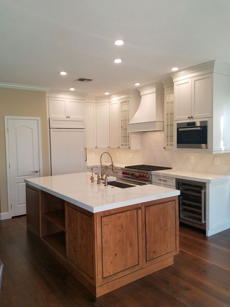 Kitchen with white cabinets, wooden island, stainless steel appliances, and wood floors.