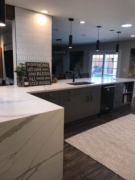Modern kitchen with gray cabinets, white countertops, and black pendant lights.