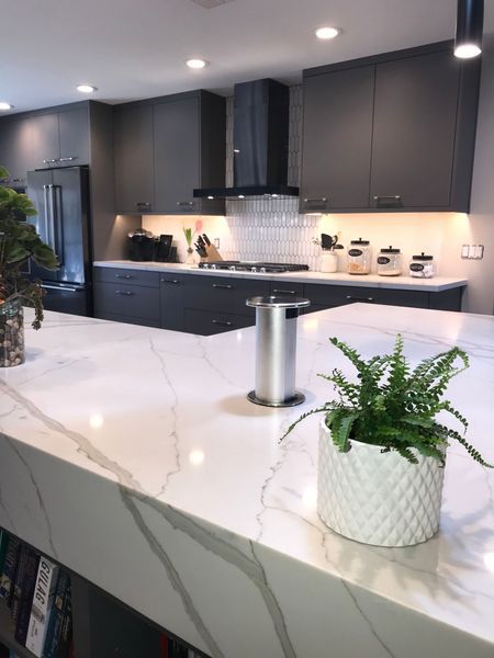 Modern kitchen with gray cabinets, white countertop, and built-in pop-up outlet.