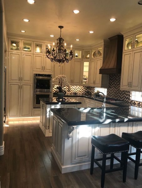 Elegant kitchen with white cabinets, dark countertops, and chandelier.