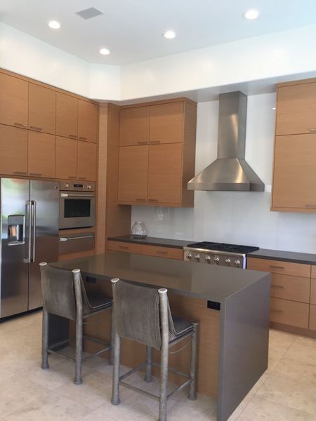 Modern kitchen with wooden cabinets, stainless steel appliances, and island with bar stools.
