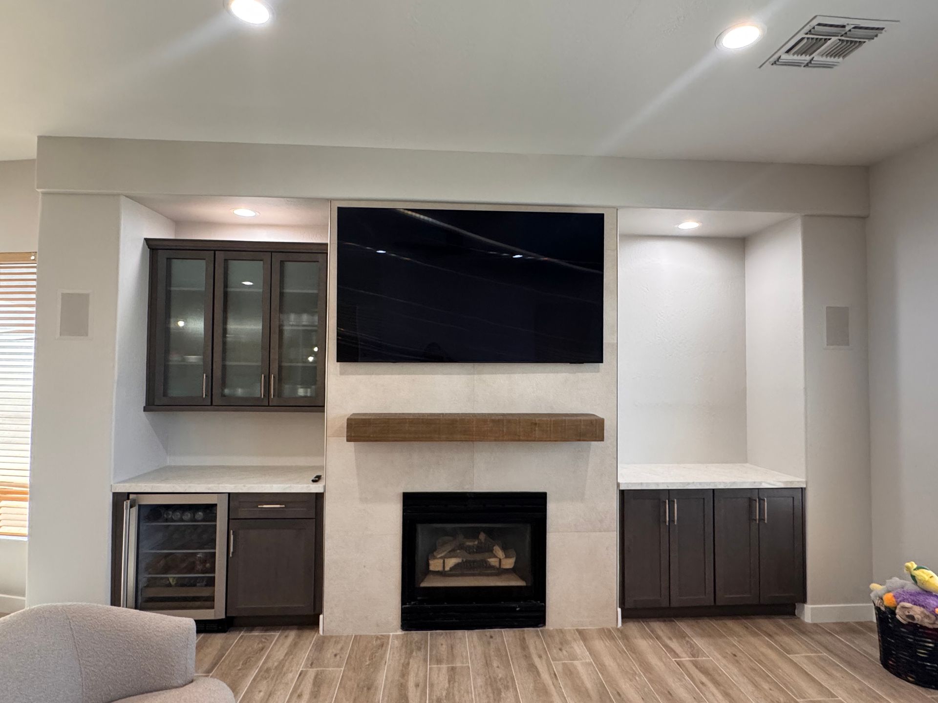 Built-in entertainment center with fireplace, TV, cabinets, and wine fridge. Gray and white tones.