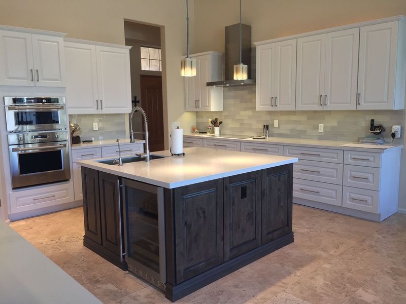 Modern kitchen with white upper cabinets, gray lowers, and an island with a wine fridge, sink, and pendant lights.