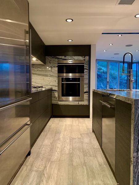 Modern kitchen with stainless steel appliances, dark cabinets, and marble accents.
