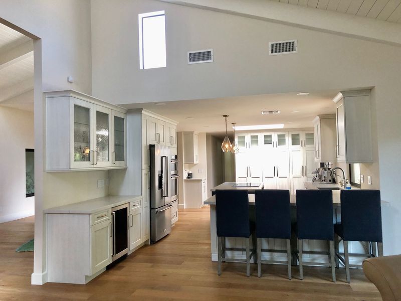 Spacious kitchen with light cabinets, stainless steel appliances, and a central island with blue chairs.