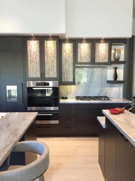 Modern kitchen with dark cabinetry, stainless steel oven, and light countertops.