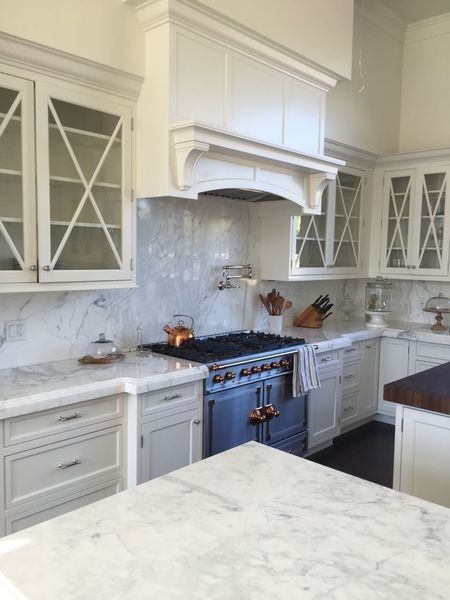 White kitchen with marble countertops, cabinets, and a blue stove.