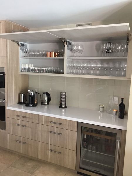 Modern kitchen bar area with cabinets, appliances, and a wine fridge.