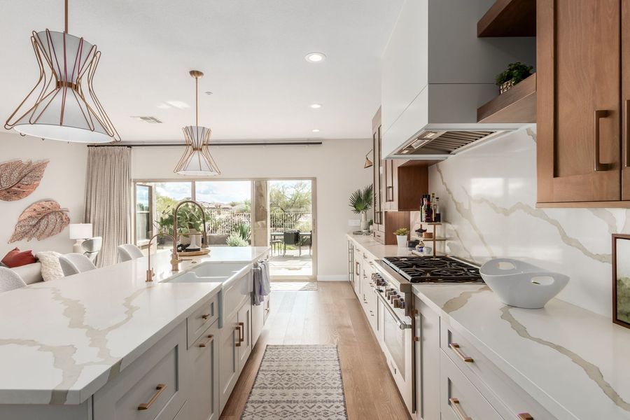 Modern kitchen with gray island, light cabinets, and large windows leading to an outdoor space.