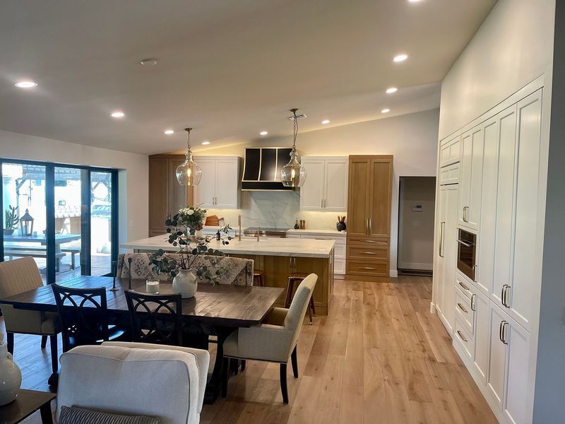 Open-concept kitchen and dining area with light wood floors, white cabinets, and a central island.