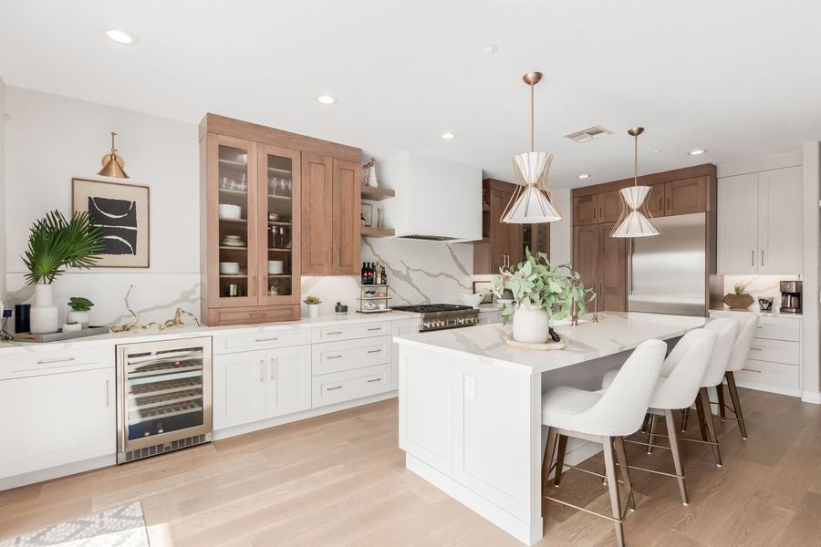 Modern kitchen with white and wood cabinetry, island with seating, stainless steel appliances.