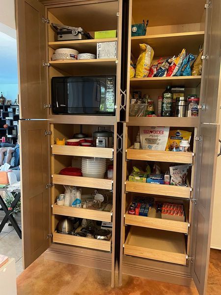 Pantry with open doors revealing shelves stocked with food and appliances.