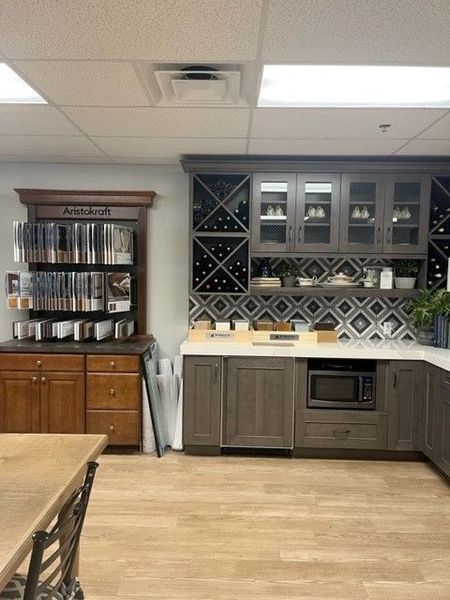 Kitchen showroom with display cabinets, wine rack, microwave, and flooring samples.