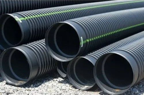 Black corrugated plastic pipes stacked on the ground.