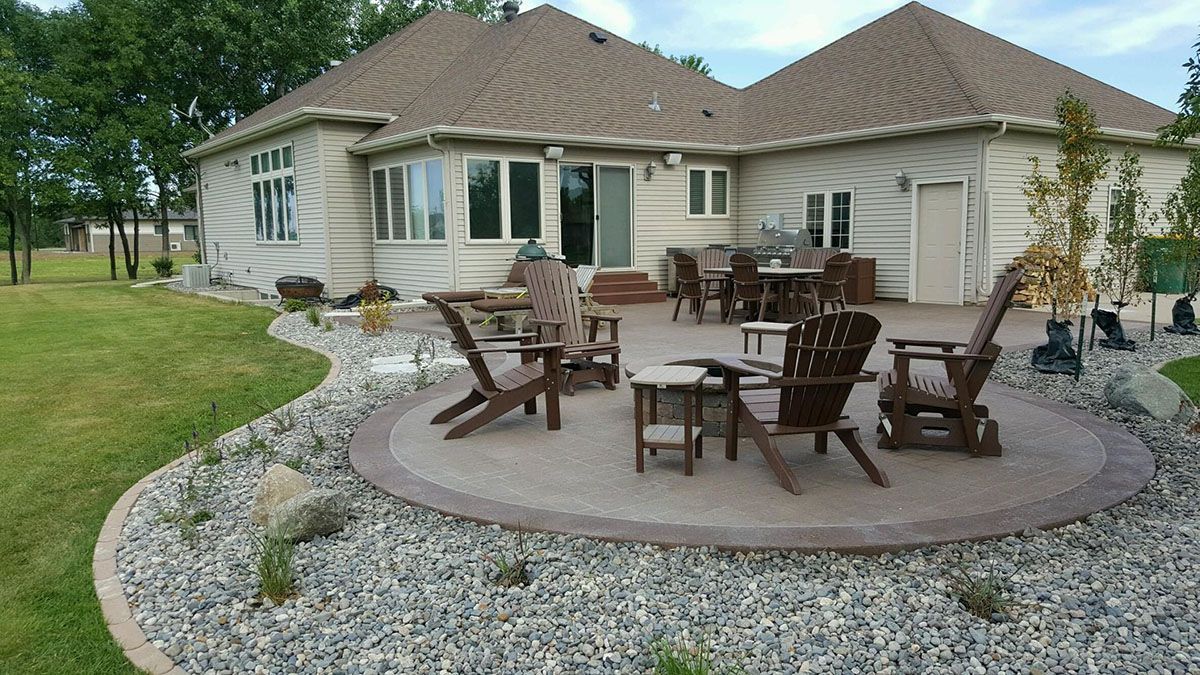 A stone patio with chairs and a fire pit