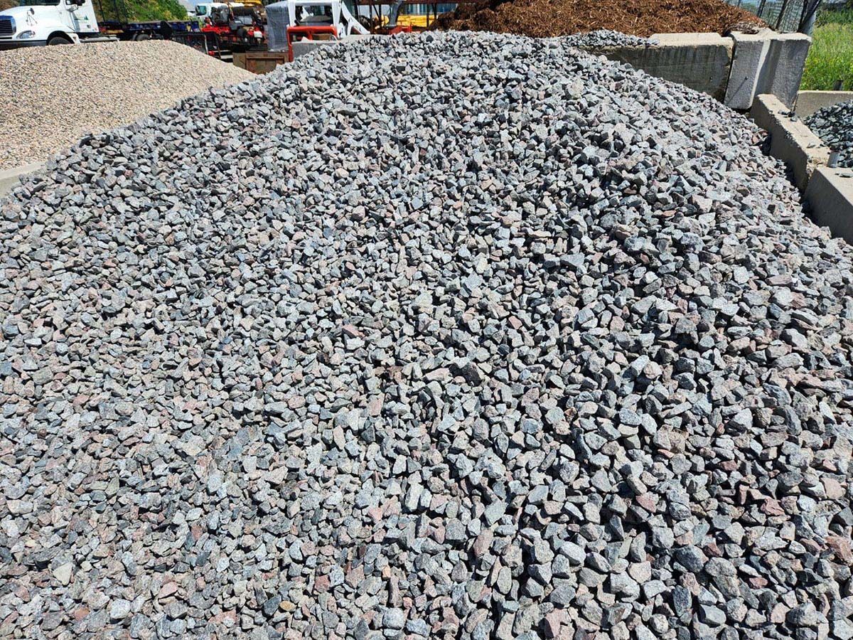 A large pile of crushed dark grey stone gravel stored in a bin