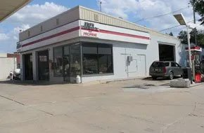Gas station with red and white trim; gray SUV parked near a garage door.