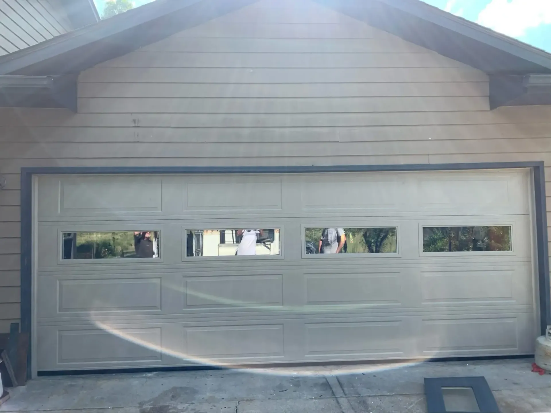 Garage with a white door covered by translucent plastic sheeting on a beige building