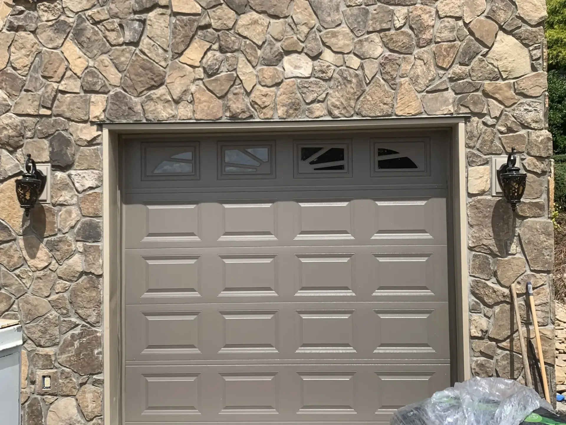 Stone house exterior with beige garage door and four small windows above it