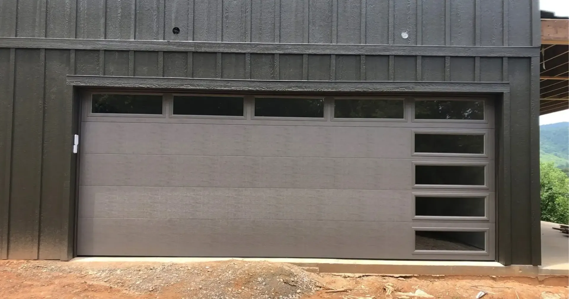Gray garage-style door with small vents set into a dark wooden building exterior